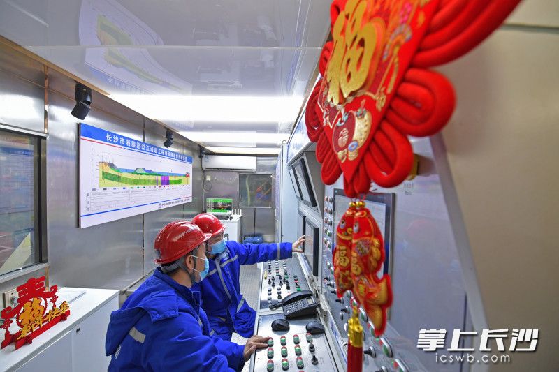 胡晓庆（左）和冯世龙（右边）正在盾构机操作室仔细研究盾构机参数。