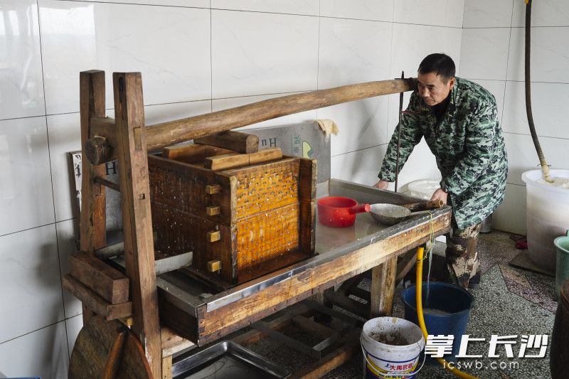 周林军正在用木质工具压制千张豆腐皮。长沙晚报全媒体记者 刘晓敏 摄