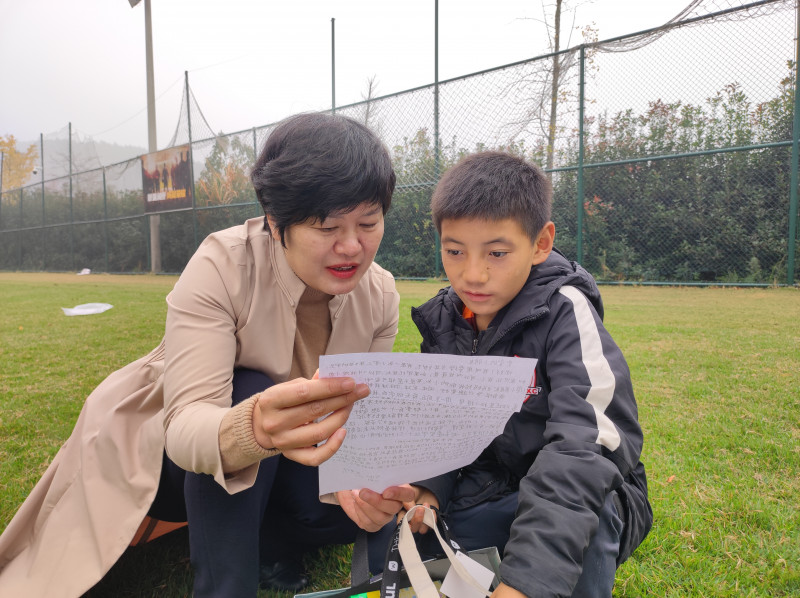 宋毅萍带彝族孩子一起看仰天湖中建小学学生写的慰问信。